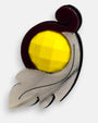 primer plano angular de la pieza acrílica de Gissa Bicalho, permitiendo apreciar el brillo y la textura de la hoja grabada junto al relieve del cabujón central facetado.