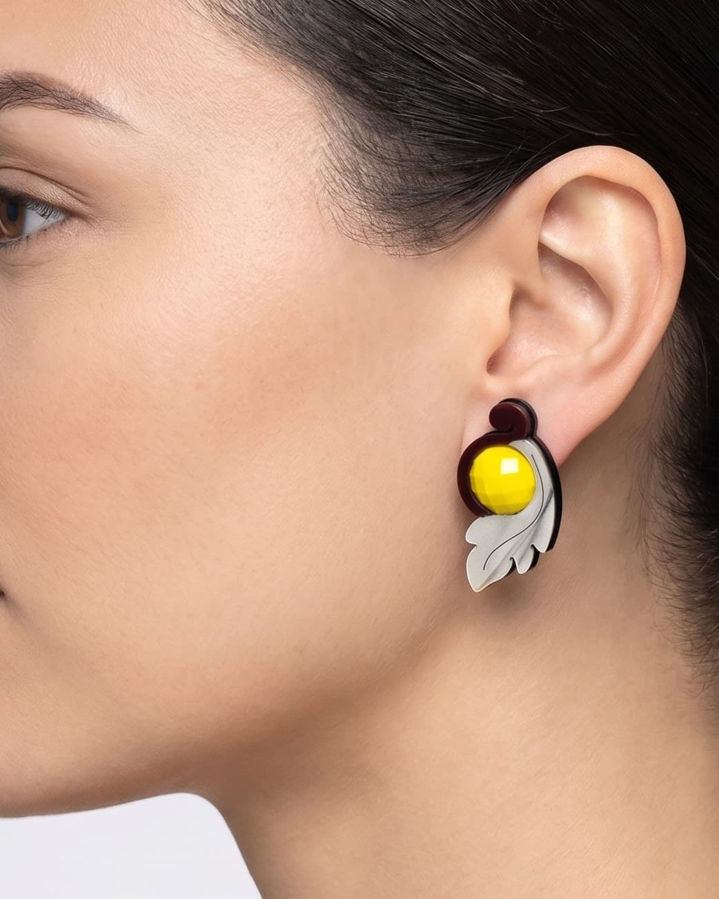 modelo de perfil luciendo uno de los pendientes de acrílico de Gissa Bicalho, mostrando su proporción y cómo se asienta elegantemente sobre el lóbulo de la oreja.