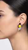 modelo de perfil luciendo uno de los pendientes de acrílico de Gissa Bicalho, mostrando su proporción y cómo se asienta elegantemente sobre el lóbulo de la oreja.