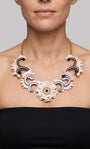 modelo luciendo el collar de acrílico de Gissa Bicalho sobre el cuello, destacando su caída, su gran tamaño decorativo y la armonía de sus formas geométricas sobre la piel.