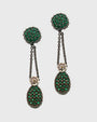 Pareja de pendientes largos Bohemme con esferas de circonitas verdes y cadenas de plata oxidada sobre fondo blanco.
