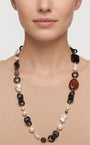 Primer plano de mujer luciendo el collar largo Amlé, resaltando la combinación de perlas y eslabones negros sobre el cuello.