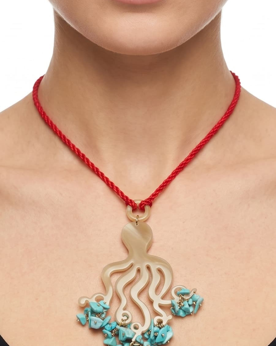 Primer plano de mujer luciendo el collar largo Amlé Octopus, resaltando la forma del colgante y el contraste del cordón rojo sobre un top negro.