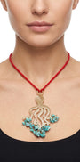 Primer plano de mujer luciendo el collar largo Amlé Octopus, resaltando la forma del colgante y el contraste del cordón rojo sobre un top negro.