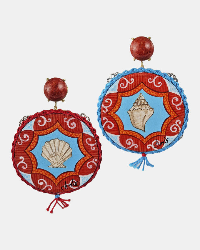 Pareja de pendientes Amlé tipo pandereta pintados a mano con conchas marinas y detalles de coral rojo sobre fondo gris claro.