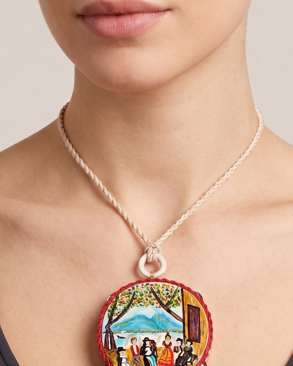 Mujer usando collar artístico Amlé con escena tradicional pintada.