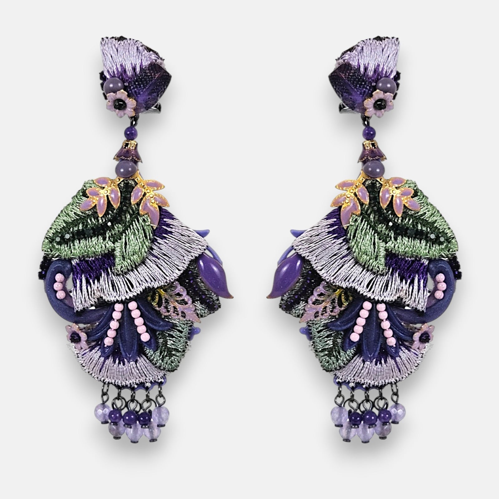Pareja de pendientes maxi Dublos con bordado de seda en violeta y verde, decorados con hojas lila y pedrería sobre fondo gris claro.