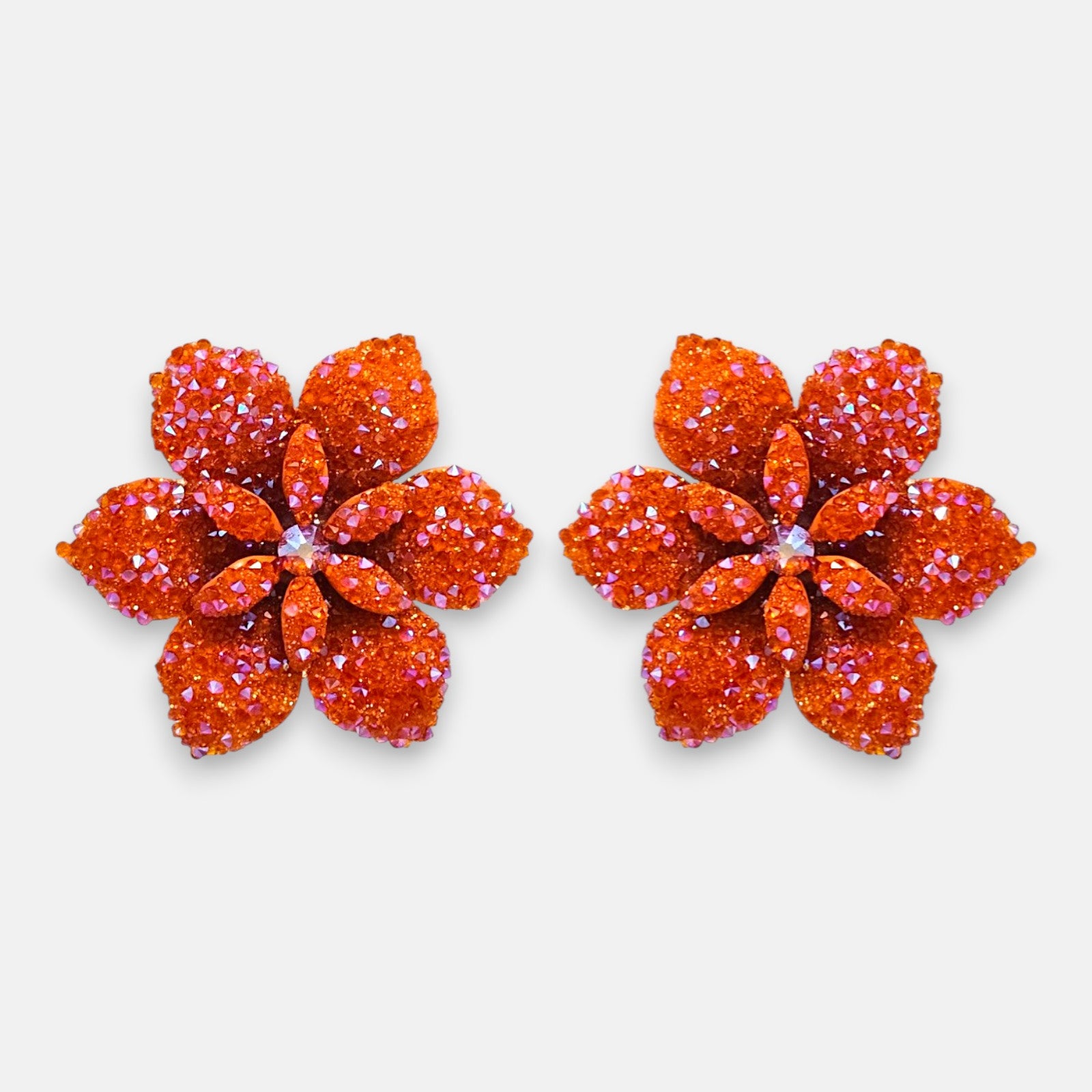 Pareja de pendientes de botón grandes en forma de flor naranja mandarina de la firma Dublos, mostrando su relieve de pétalos y el brillo de sus cristales iridiscentes.