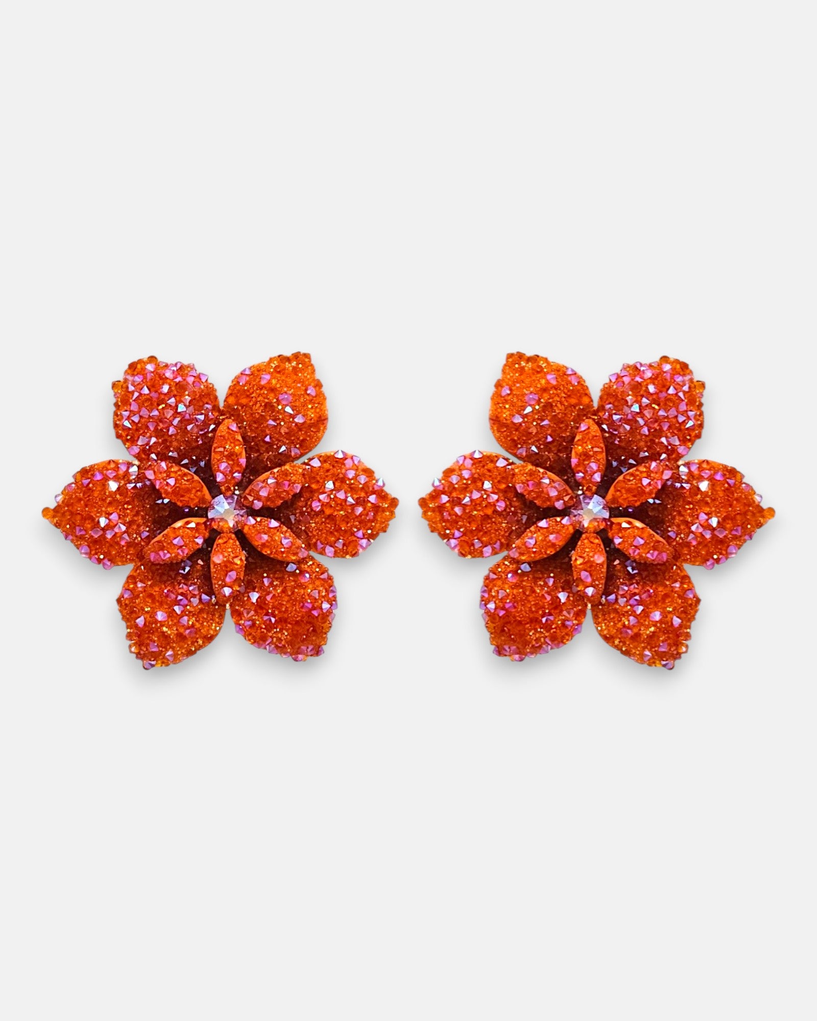 Pareja de pendientes de botón grandes en forma de flor naranja mandarina de la firma Dublos, mostrando su relieve de pétalos y el brillo de sus cristales iridiscentes.