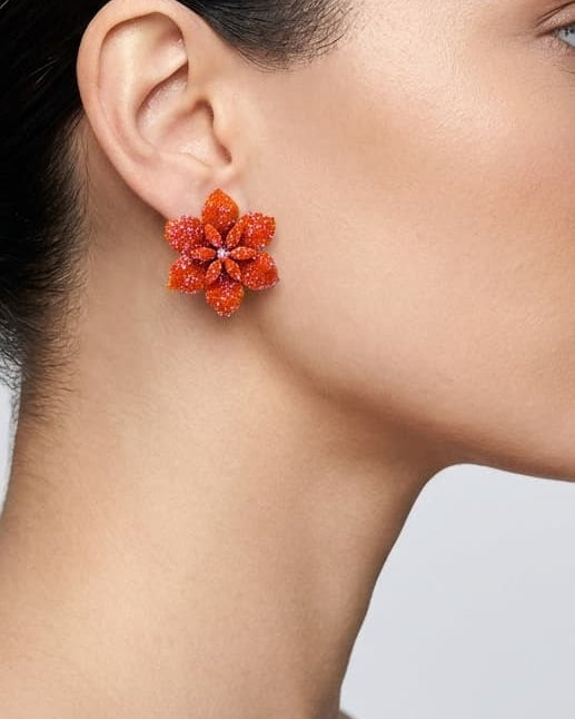 Vista de un maxipendiente de botón Flor de Caléndula colocado en la oreja de una modelo, detallando su volumen tridimensional y cómo queda pegado al lóbulo.