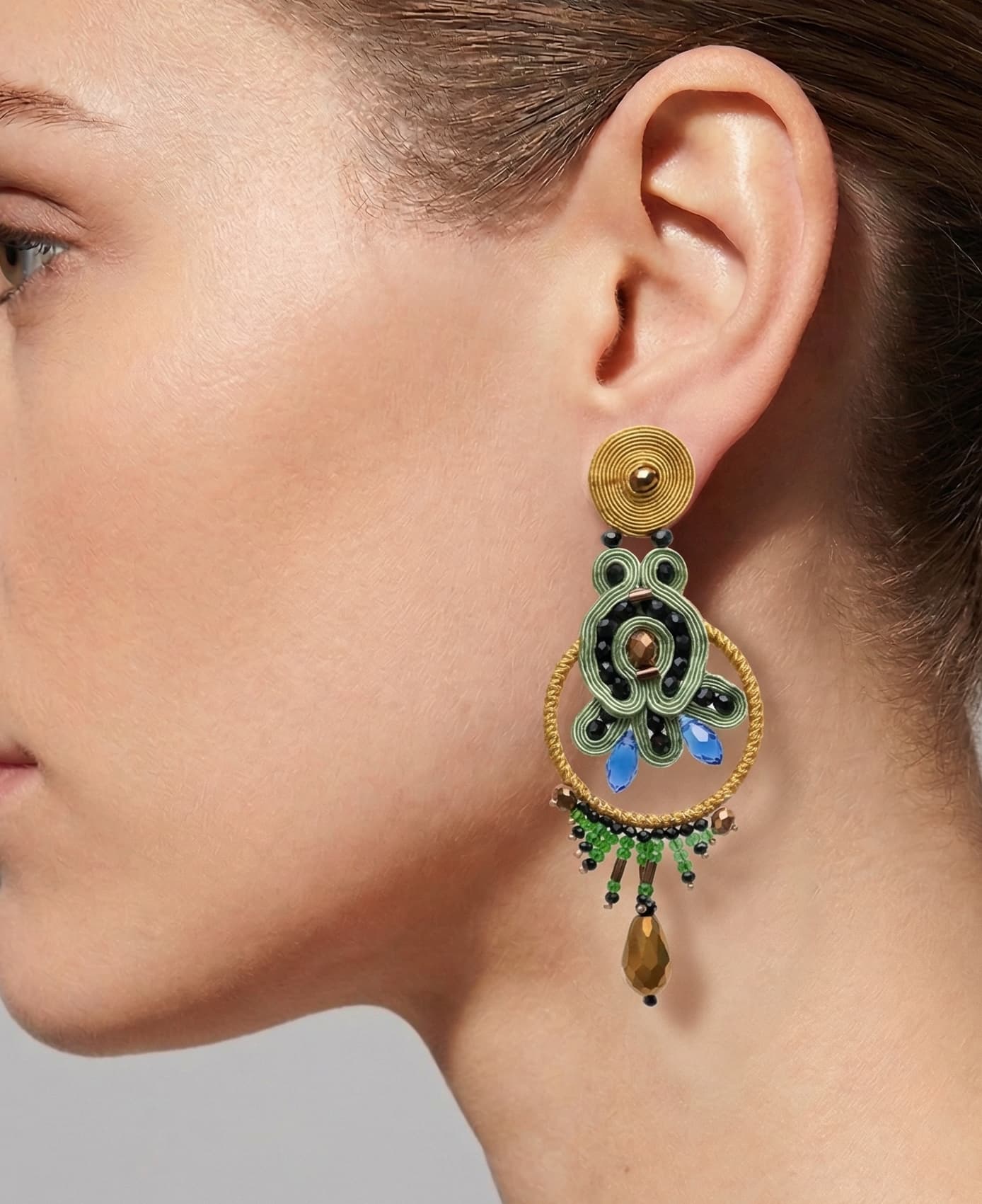 Mujer luciendo los pendientes statement Almona, destacando su tamaño y cómo el color verde ilumina el rostro.