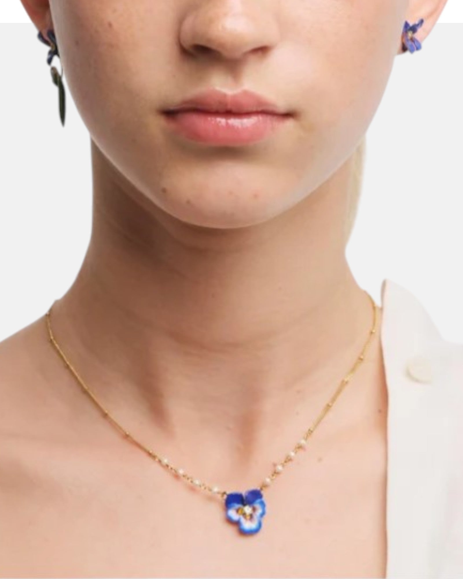 Modelo luciendo el collar de flor pensamiento azul y perlas de cultivo de Les Néréides a la altura de la clavícula.