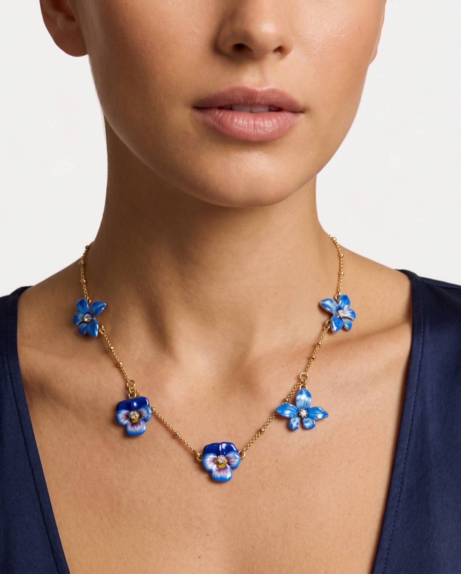 Modelo luciendo el collar corto de flor pensamiento azul de Les Néréides ajustado sobre la clavícula.
