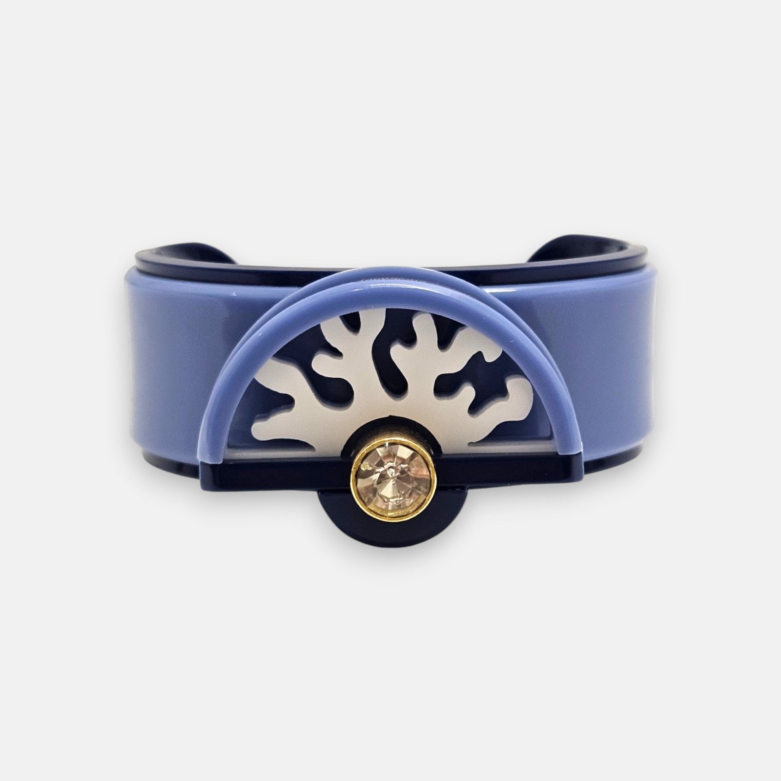vista frontal del brazalete rígido de Gissa Bicalho realizado en acrílico de alta calidad con un aplique semicircular de diseño de coral y un cristal redondo brillante en el centro.
