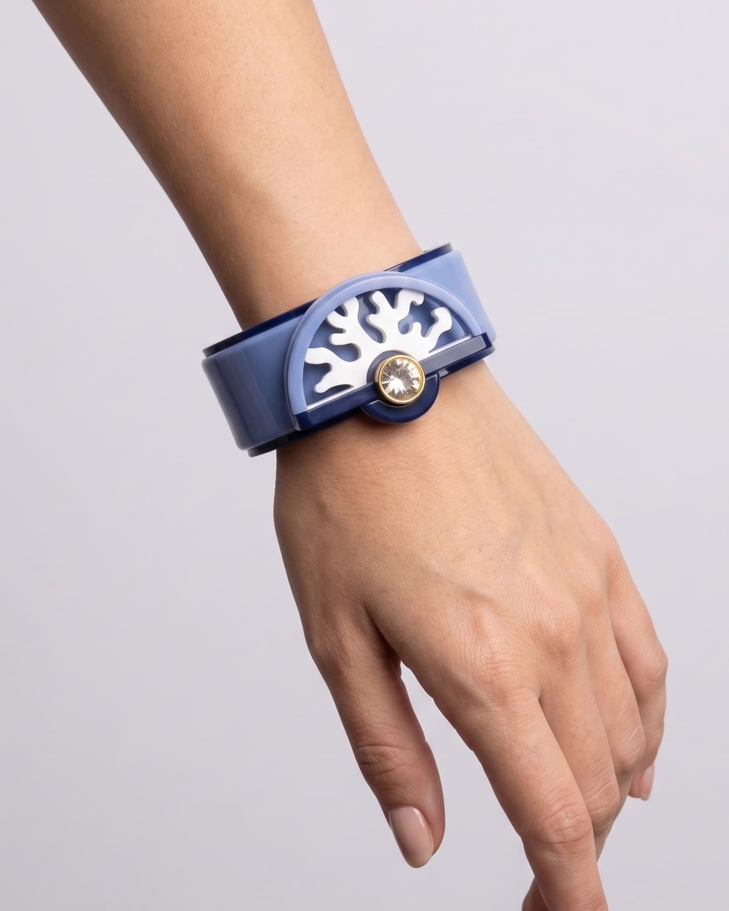 brazalete acrílico de Gissa Bicalho colocado en la muñeca de una modelo, destacando su escala, su acabado pulido brillante y su ajuste ergonómico.