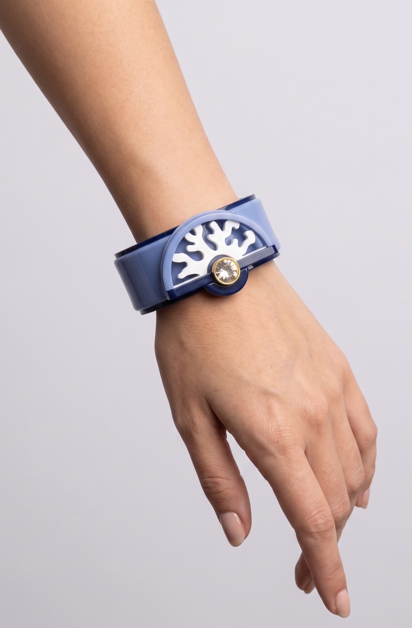 brazalete acrílico de Gissa Bicalho colocado en la muñeca de una modelo, destacando su escala, su acabado pulido brillante y su ajuste ergonómico.