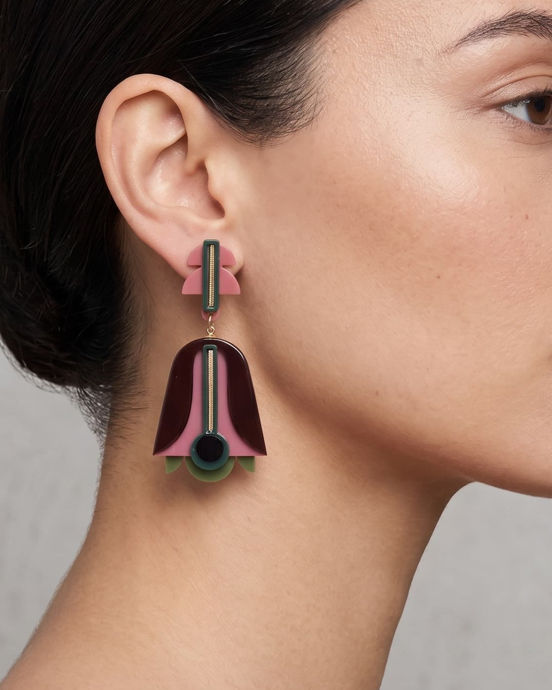 Vista de perfil de los pendientes escultóricos de acrílico de Gissa Bicalho colocados en una modelo, detallando su caída de aire Art Déco y su proporción maxi.