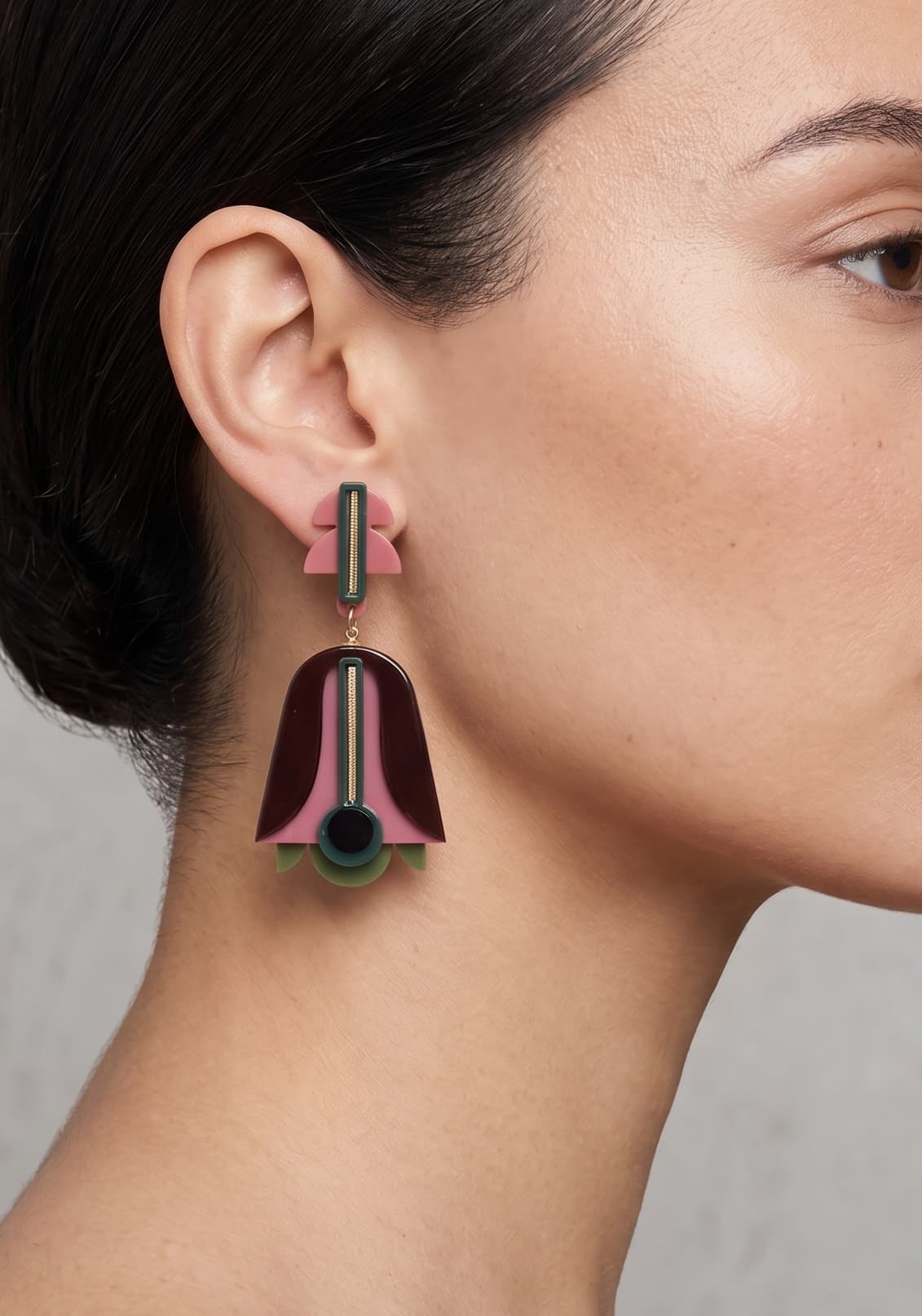 Vista de perfil de los pendientes escultóricos de acrílico de Gissa Bicalho colocados en una modelo, detallando su caída de aire Art Déco y su proporción maxi.