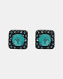 Pareja de pendientes de botón cuadrados Bohemme con piedra turquesa central y orla de circonitas azules sobre plata oxidada.