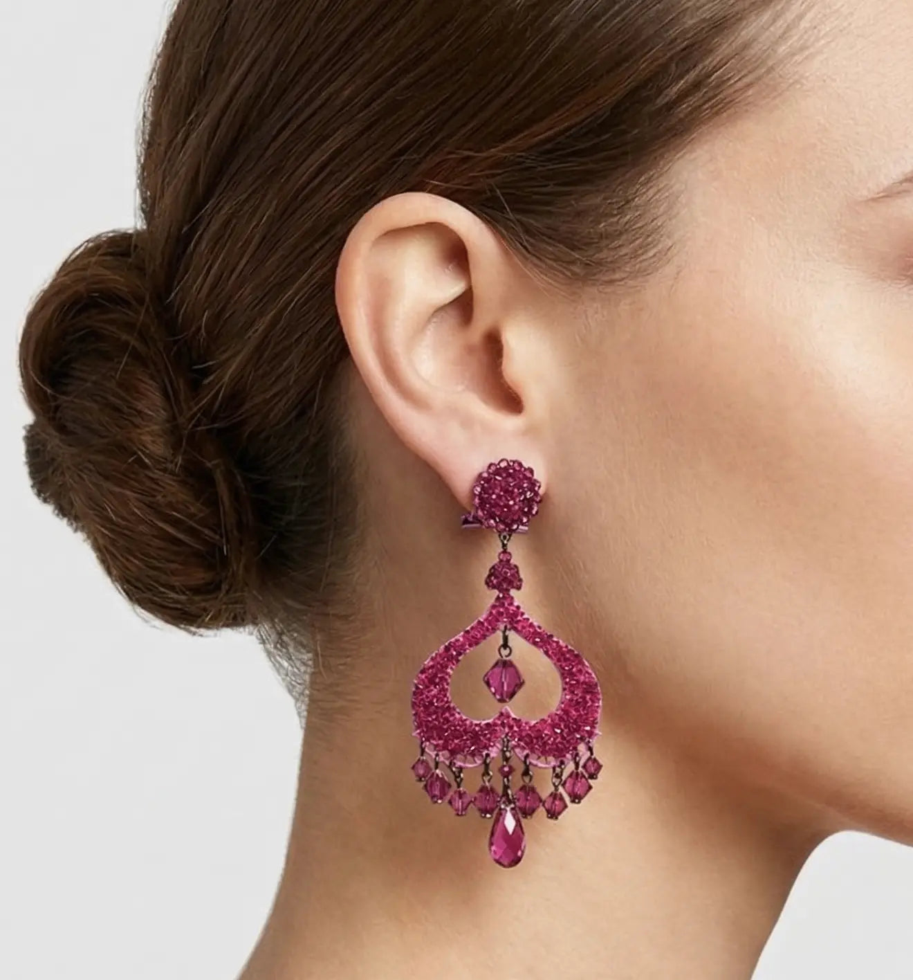 Mujer luciendo los pendientes Dublos de Swarovski en color magenta, resaltando su brillo y elegancia de gala.