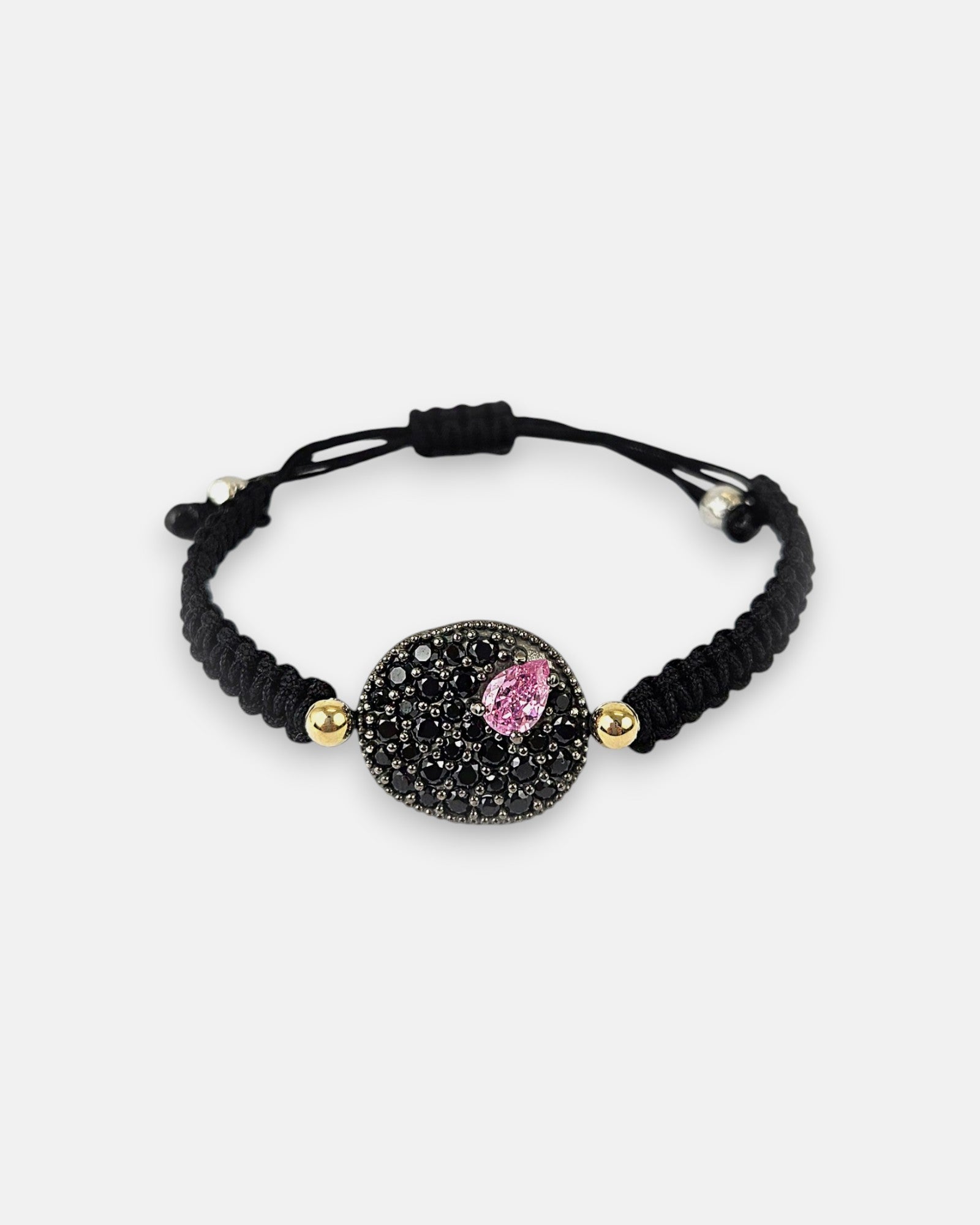 Pulsera de cordón negro Bohemme con medallón circular de espinelas negras y piedra central rosa.