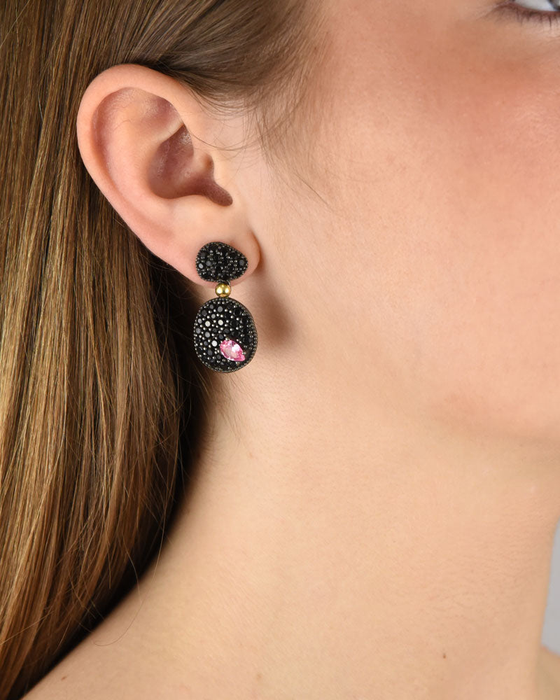 Mujer luciendo los pendientes de plata y cuarzo rosa de Bohemme, resaltando su brillo oscuro y movimiento elegante.