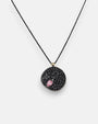 Colgante circular Bohemme con medalla de espinelas negras y detalle de piedra rosa sobre cadena negra.