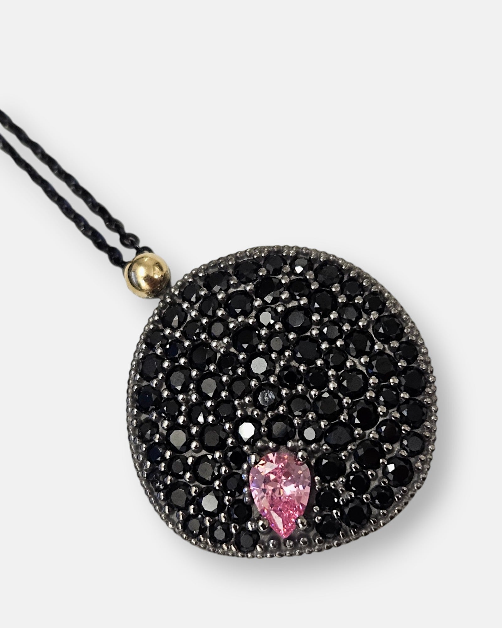 Primer plano del medallón Bohemme mostrando el pavé de espinelas, la piedra rosa y la unión en oro de 18K.