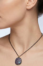 Mujer luciendo el collar corto Bohemme Musa violeta, destacando la elegancia del medallón sobre el escote.