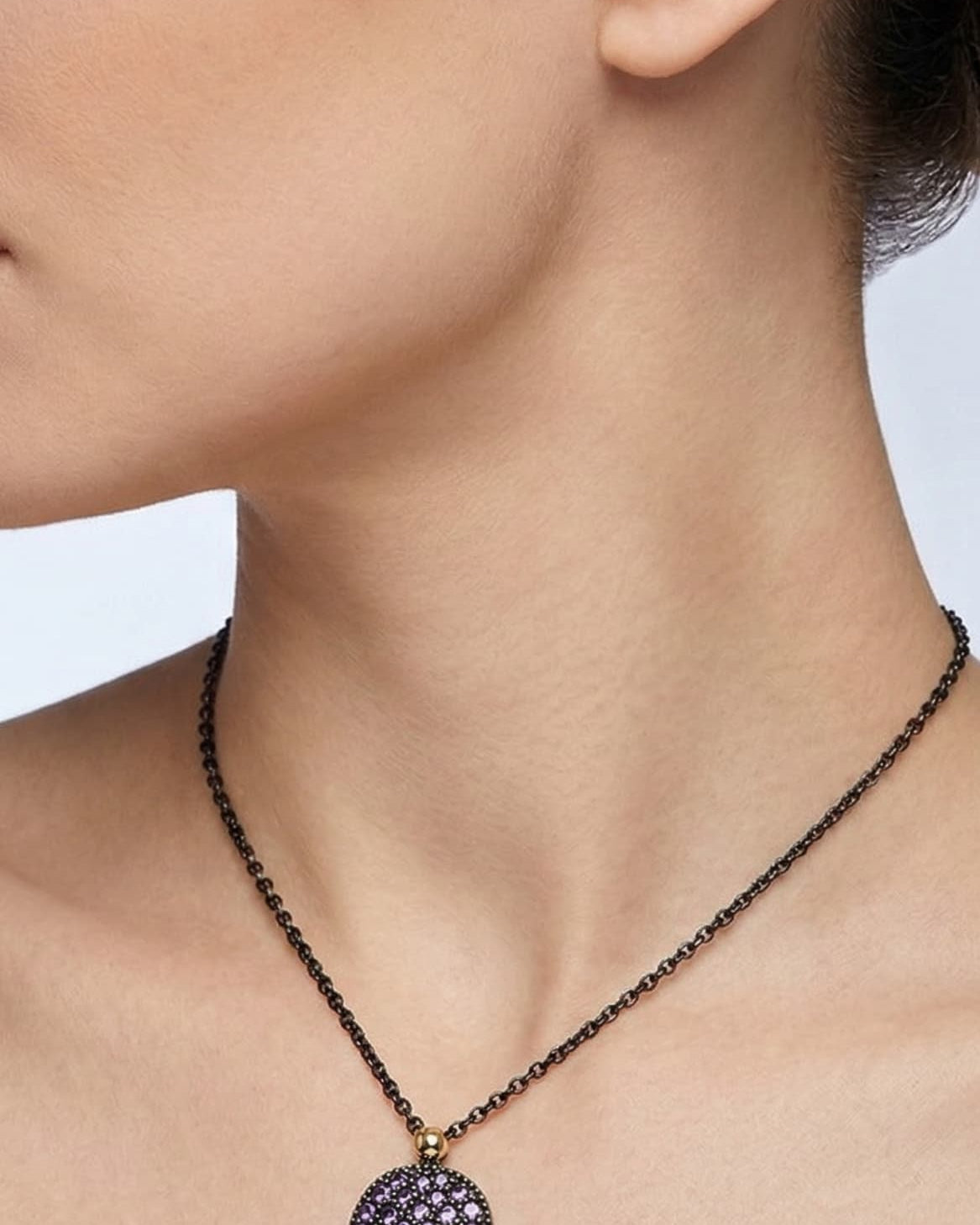 Mujer luciendo el collar corto Bohemme Musa violeta, destacando la elegancia del medallón sobre el escote.