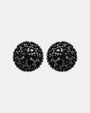 Pareja de pendientes de botón circulares Bohemme con pavé de espinelas negras sobre fondo gris claro.