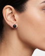 Mujer luciendo los pendientes de botón negros de Bohemme, resaltando su brillo discreto y ajuste perfecto al lóbulo.
