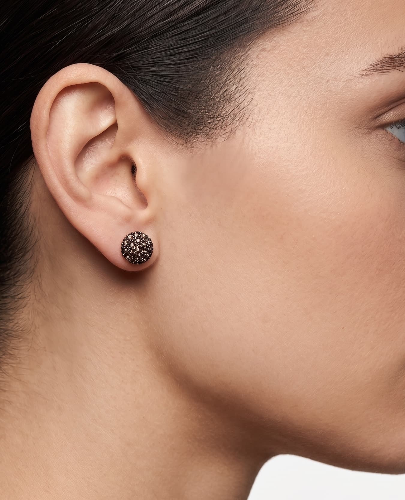 Mujer luciendo los pendientes de botón ahumados de Bohemme, resaltando su brillo profundo y diseño artesanal en el lóbulo.