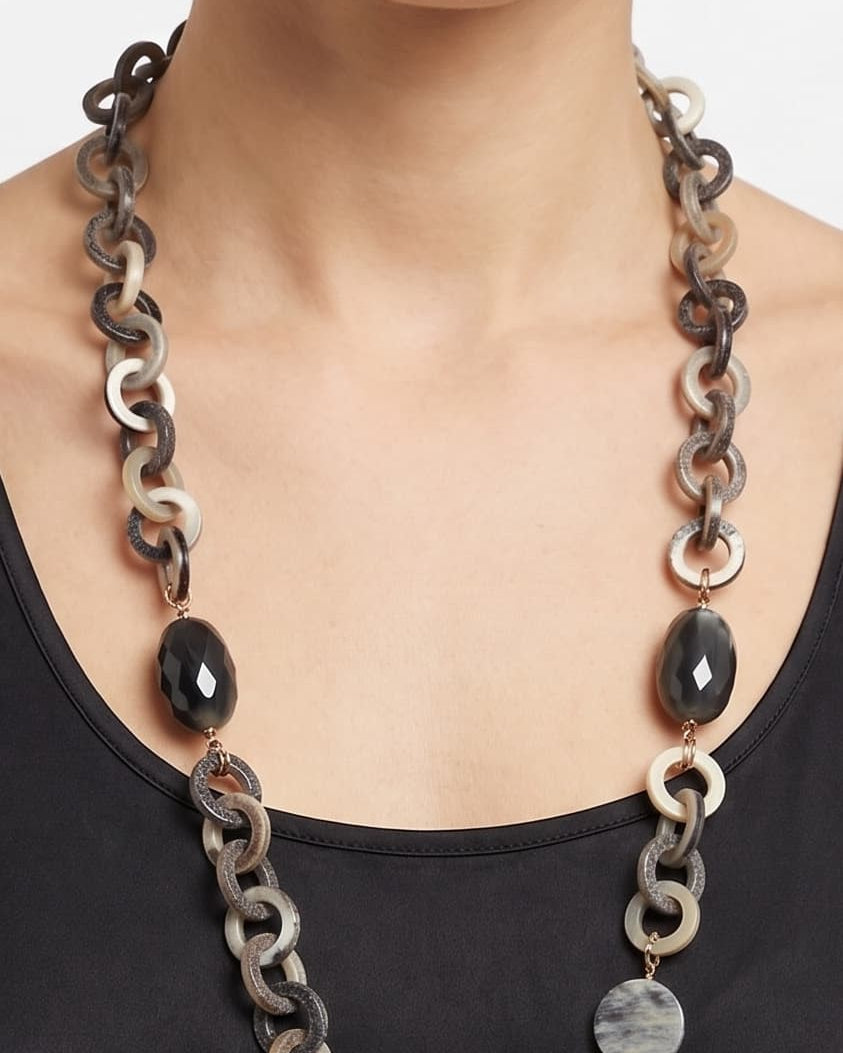 Mujer luciendo el collar largo Amlé, resaltando la elegante caída de los eslabones de cuerno sobre un top negro.