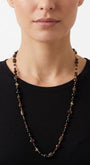 Primer plano de mujer luciendo el collar largo Amlé, resaltando el diseño elegante y los tonos tierra sobre un top negro.