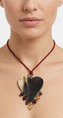 Mujer luciendo el collar de corazón de cuerno Amlé, resaltando su caída y el contraste del cordón burdeos sobre su piel.