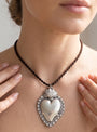 Mujer luciendo el colgante de corazón sagrado, resaltando el tamaño y el estilo de la joya en el cuello.