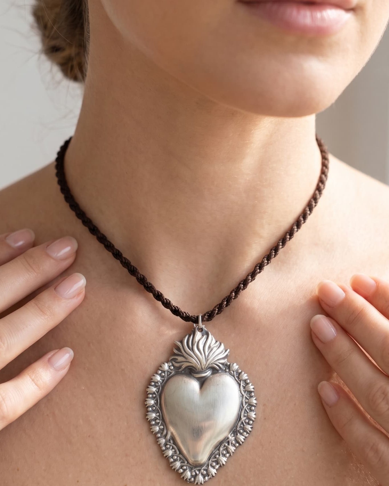 Mujer luciendo el colgante de corazón sagrado, resaltando el tamaño y el estilo de la joya en el cuello.