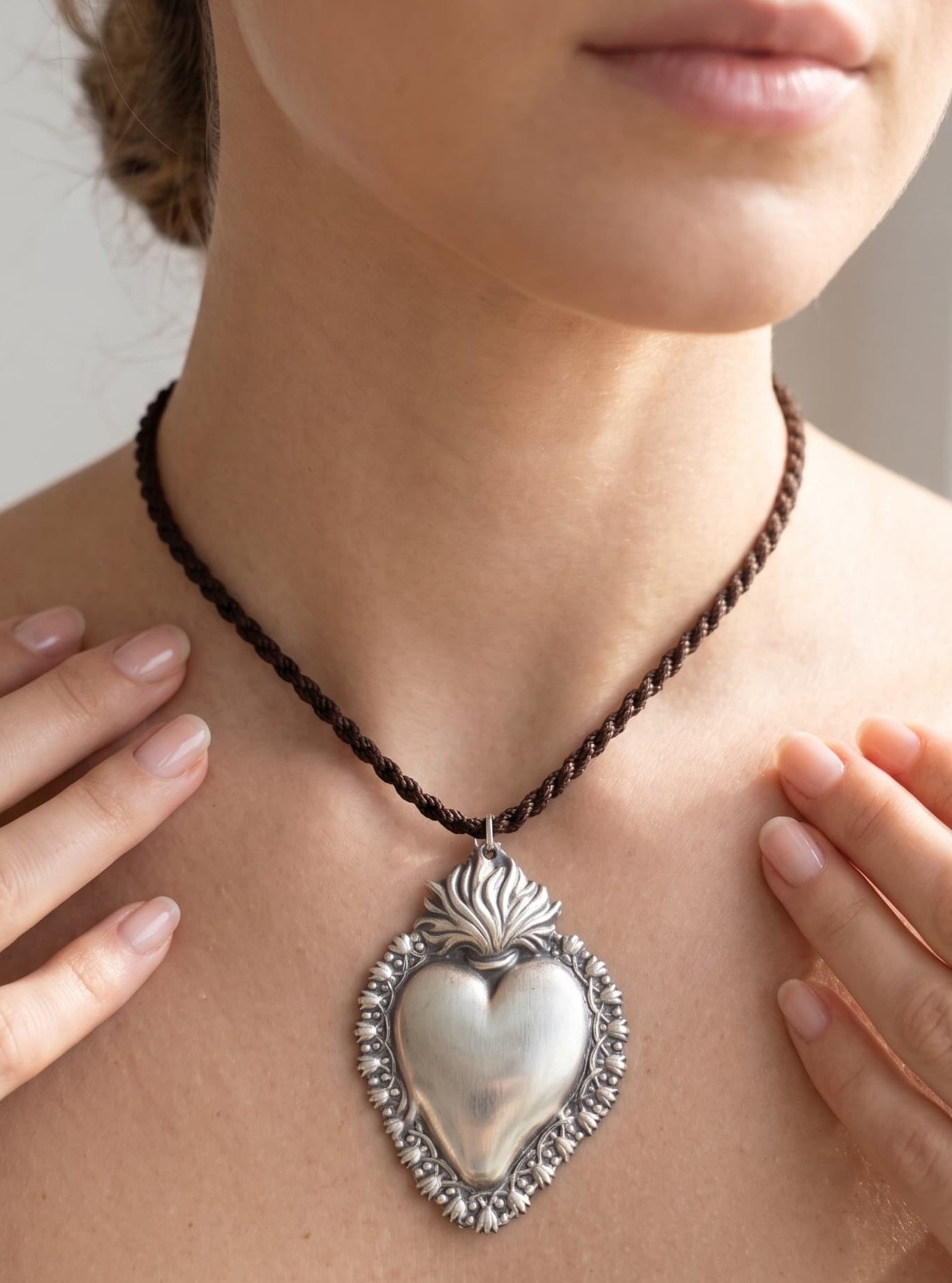Mujer luciendo el colgante de corazón sagrado, resaltando el tamaño y el estilo de la joya en el cuello.