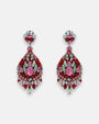 Par de pendientes largos Dublos tipo chandelier con cristales en tonos rosa y verde sobre fondo neutro.