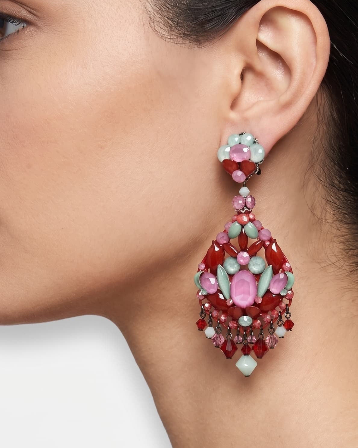 Primer plano de perfil de mujer luciendo los pendientes largos Dublos, resaltando el contraste de los cristales rosas y verdes.