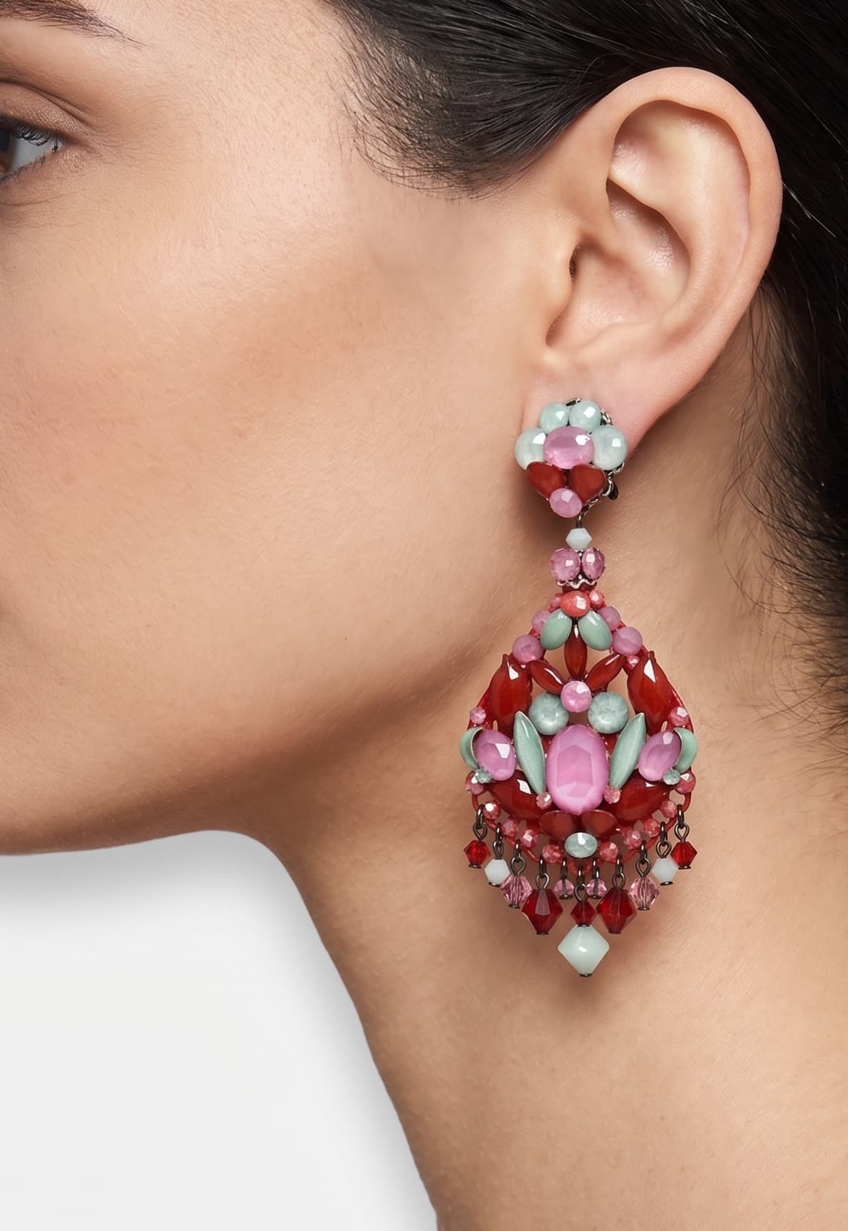 Primer plano de perfil de mujer luciendo los pendientes largos Dublos, resaltando el contraste de los cristales rosas y verdes.