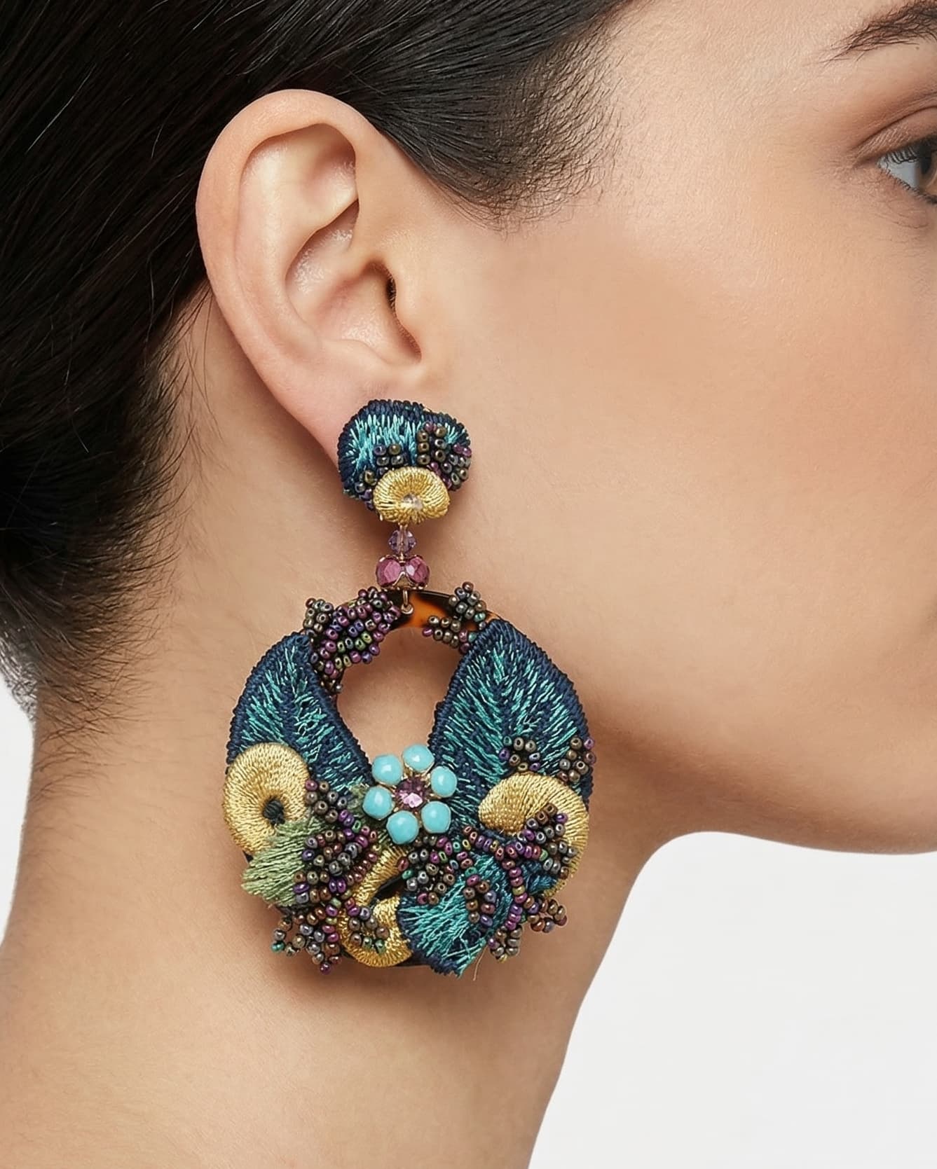 Mujer luciendo los pendientes maxi Dublos Jardín de Pavo Real, resaltando el volumen, los colores joya y la elegancia del diseño.