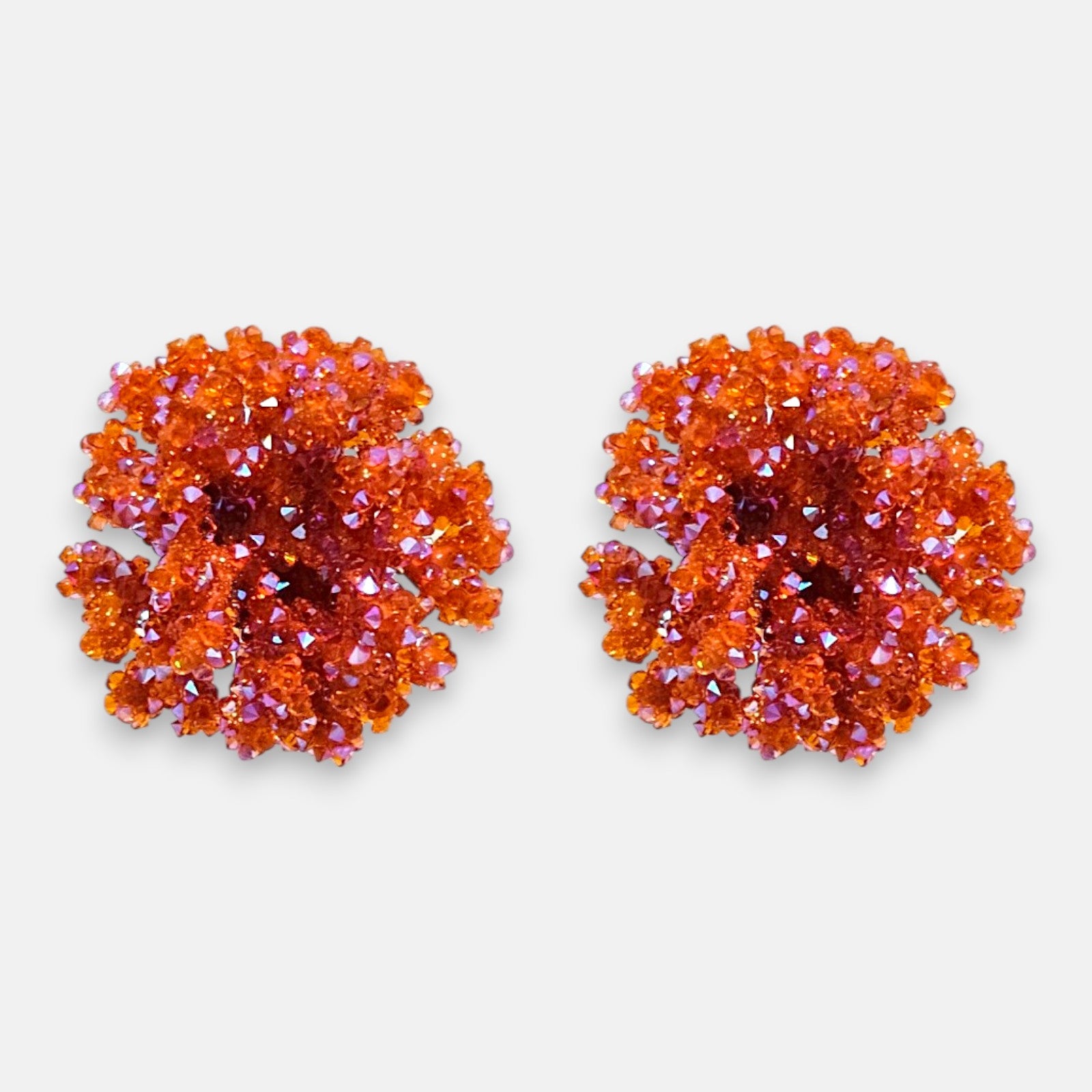 Pareja de pendientes de botón redondos en color naranja mandarina de la firma Dublos, mostrando su textura esférica y el brillo de sus cristales iridiscentes.