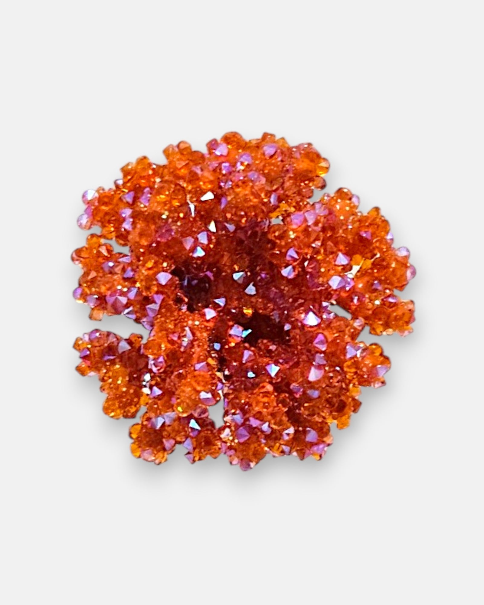 Primer plano macro de un pendiente artesanal Dublos redondo, detallando la superficie texturizada naranja y el brillo tridimensional de los cristales facetados.