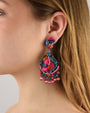 Mujer luciendo los pendientes Dublos Bazar, resaltando su vibrante color fucsia y cómo iluminan el rostro con elegancia.