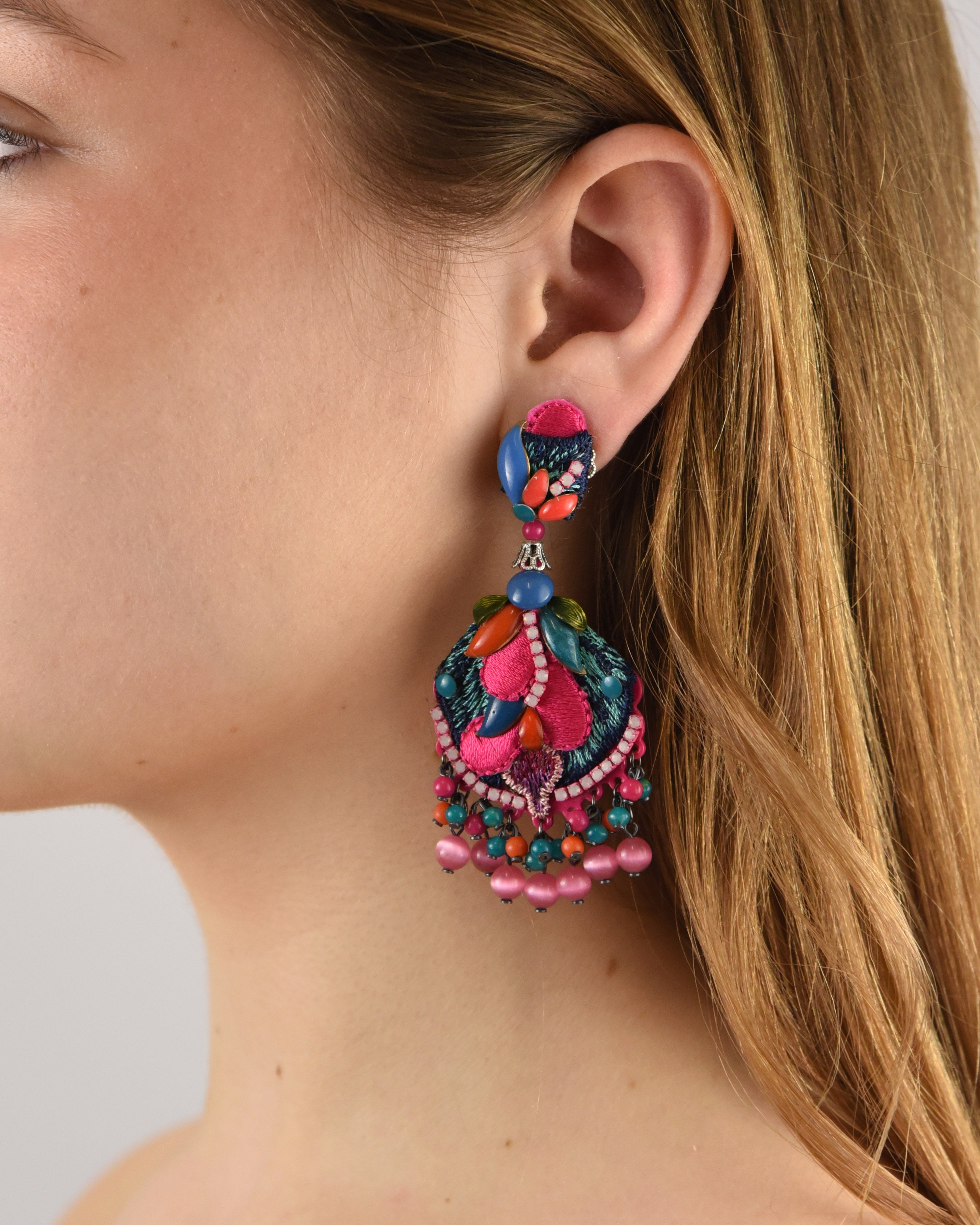 Mujer luciendo los pendientes Dublos Bazar, resaltando su vibrante color fucsia y cómo iluminan el rostro con elegancia.