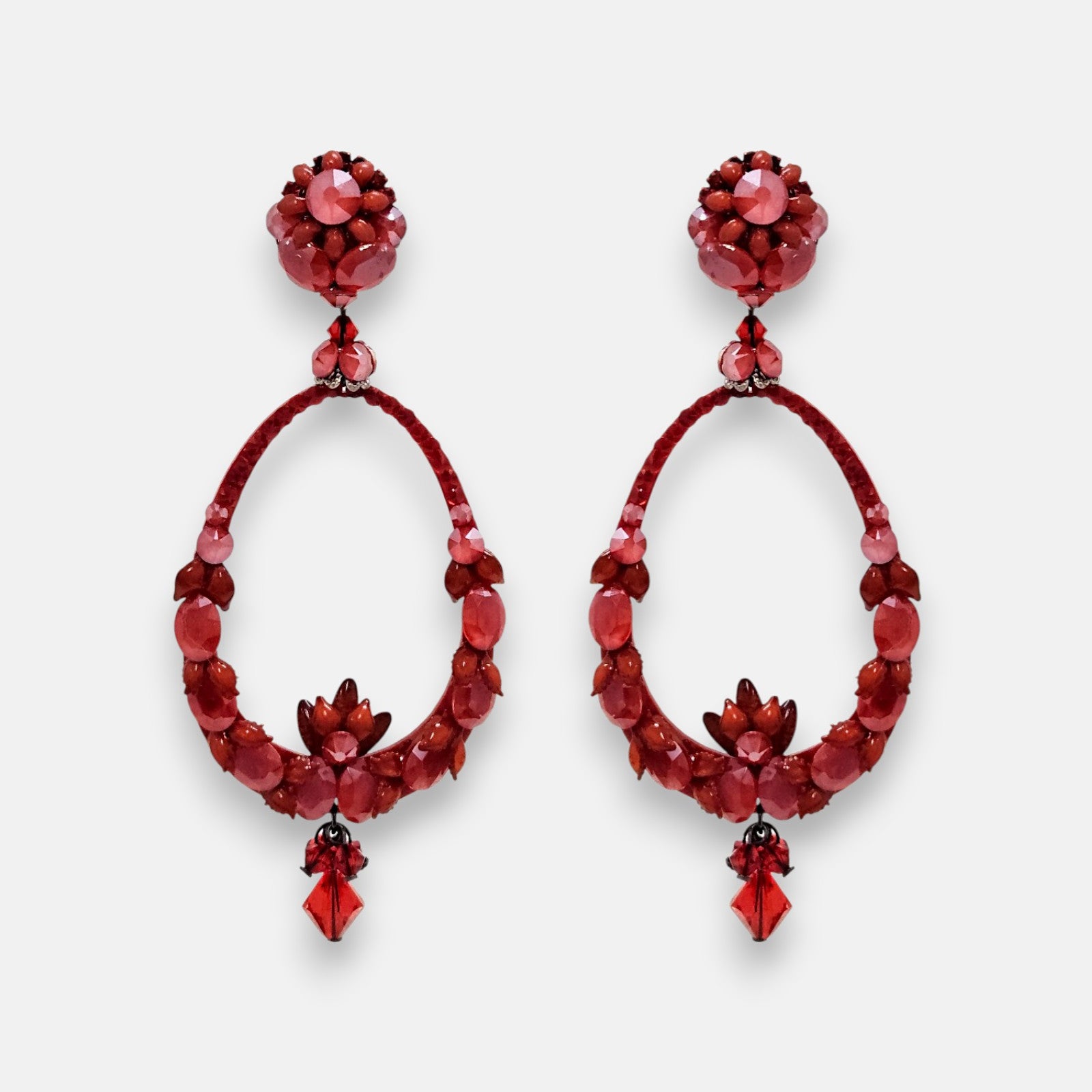 Par de pendientes de aro estilo gota Dublos en tonos rojos con cristales tallados sobre fondo neutro.