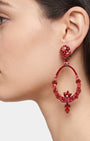 Primer plano de perfil de mujer luciendo los pendientes Dublos en rojo, resaltando el diseño floral y el movimiento del cristal.