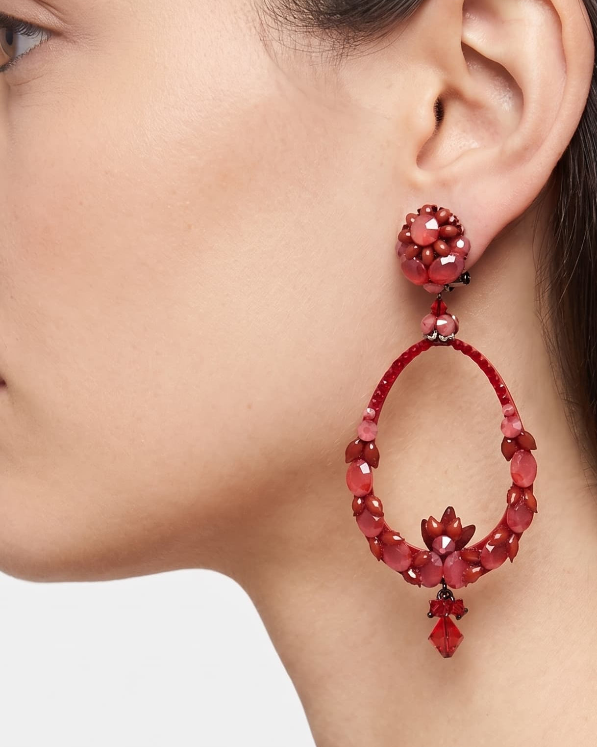 Primer plano de perfil de mujer luciendo los pendientes Dublos en rojo, resaltando el diseño floral y el movimiento del cristal.